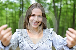 Happy woman saying come here beckoning in a park