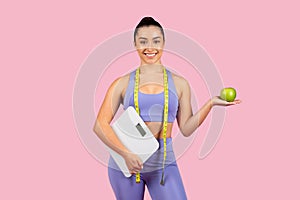 Happy woman with scale and apple, fitness concept