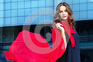 Happy woman with a scarf. Portrait of the beautiful girl.Fashionable portrait of a girl model with waving red silk scarf.