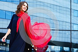 Happy woman with a scarf. Portrait of the beautiful girl. Fashionable portrait of a girl model with waving red silk scarf.