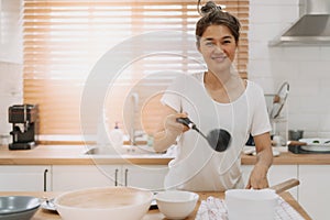 Happy woman serving soup into the small bowl.