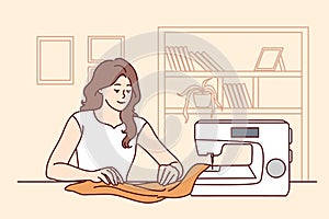 Happy woman sewing on machine at home