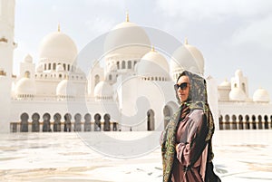 Happy woman in The Sheikh Zayed Grand Mosque. Female tourist with headscarf and dress in Adu Dhabi.