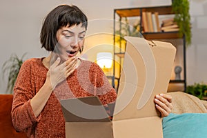 Happy woman shopper unpacking cardboard box delivery parcel online shopping purchase at home room
