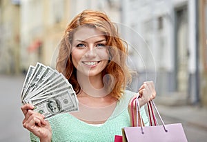 Happy woman with shopping bags and money on street