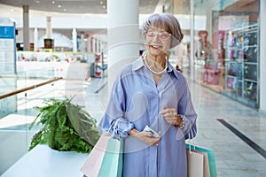 Happy woman with shopping bags over mall store showcase