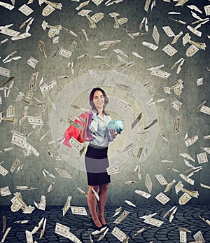 Happy woman with shopping bags and piggy bank standing under money rain