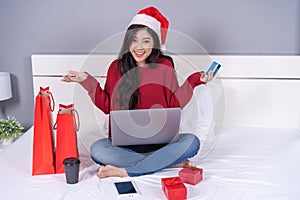 Happy woman shopping online for Christmas gift with computer lap