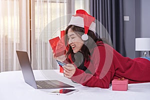 Happy woman shopping online for Christmas gift with computer lap