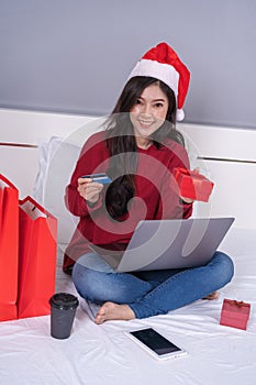 Happy woman shopping online for Christmas gift with computer lap