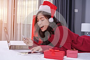 happy woman shopping online for Christmas gift with digital tablet and credit card on bed