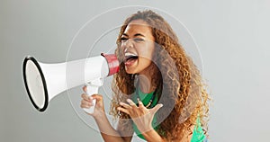 Happy woman, shouting and pointing with megaphone for motivation on a gray studio background. Excited female person