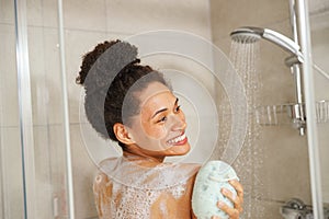 Happy woman showering, washing her back with a sponge in the bathroom