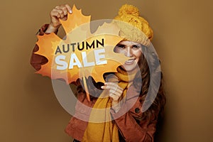 Happy woman showing autumn sale banner on beige background