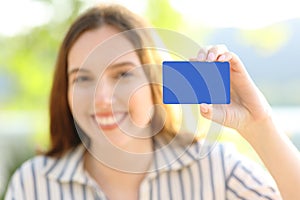 Happy woman showing blank credit card at camera