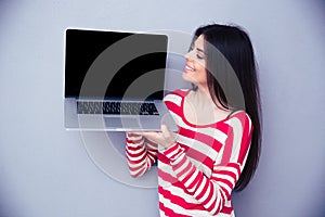 Happy woman showing blank laptop screen