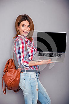 Happy woman showing blank laptop screen