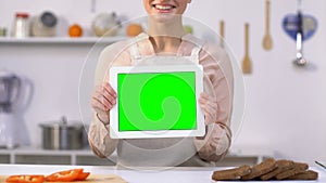 Happy woman showing green screen tablet at camera, online recipes application