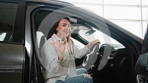 Happy woman showing keys to her new car at the dealership. Right hand drive car