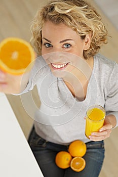 happy woman showing orange at home