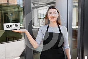 happy woman showing reopen banner on door glass