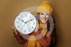 Happy woman showing round clock remind about autumn time change