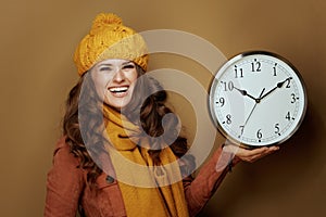 Happy woman showing round clock remind about fall time change