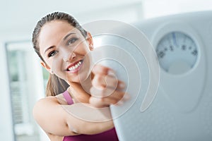 Happy woman showing a scale