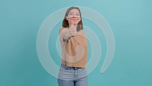 Happy woman showing thumbs up gesture, isolated over a turquoise background.