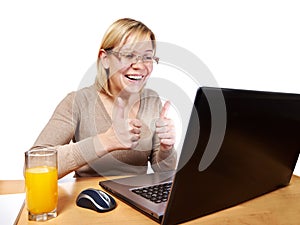Happy woman showing thumbs up looking at laptop screen