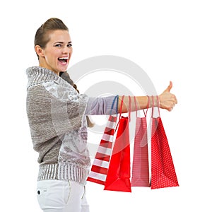 Happy woman showing thumbs up with shopping bags