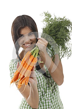 Happy woman shows on a bunch of carrots