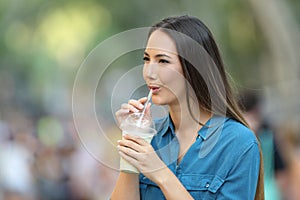 Happy woman sipping milk shake in the street