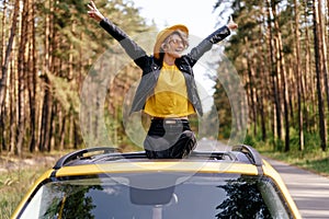 Happy Woman Sitting on Car Sunroof Freedom Concept