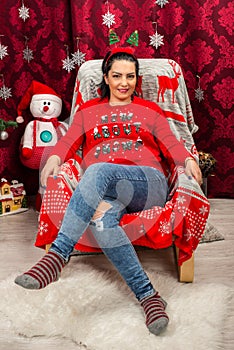 Happy woman sitting on chair with Christmas tree