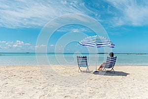 Happy woman sitting in chair on a tropical beach. Summer vacation concept