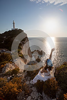 happy woman sitting at the cliff view view of Lefkada island lighthouse