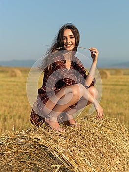 Happy woman sitting on a hay stack