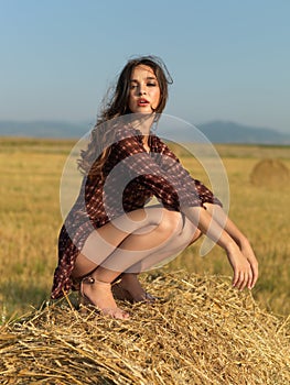 Happy woman sitting on a hay stack