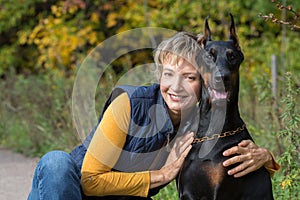 Happy woman is sitting and hugging the dog in a