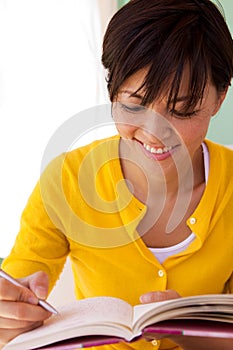 Happy woman sitting inside writing in a journal. photo