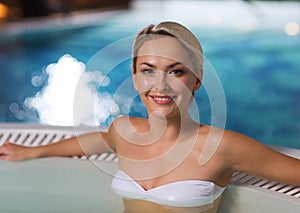 Happy woman sitting in jacuzzi at poolside