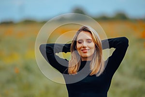 Happy Woman Sitting in a Meadow Enjoying Fresh Air