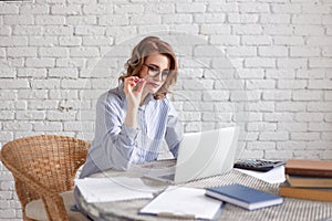 Happy woman sitting at office and holding a pen in her mouth.