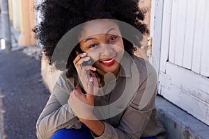 Happy woman sitting outside on mobile phone call