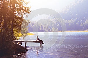 Happy woman sitting on the pier and smiling, happiness or inspiration concept