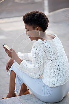 Happy woman sitting and sending text message on cellphone