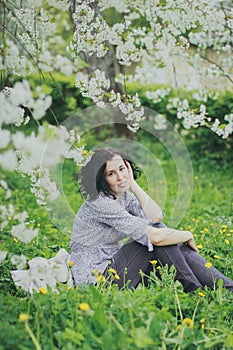 Happy woman sitting in the spring cherry garden