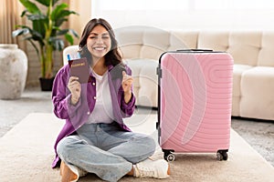Happy woman sitting with suitcase and passport