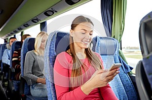 Happy woman sitting in travel bus with smartphone